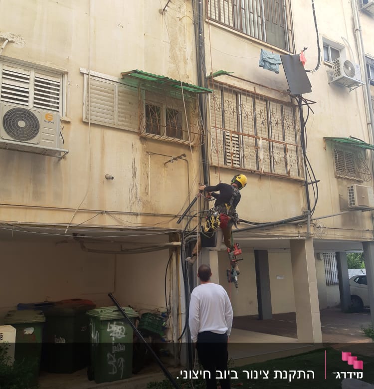 אדם עם קסדה צהובה עובד על צינורות חיצוניים